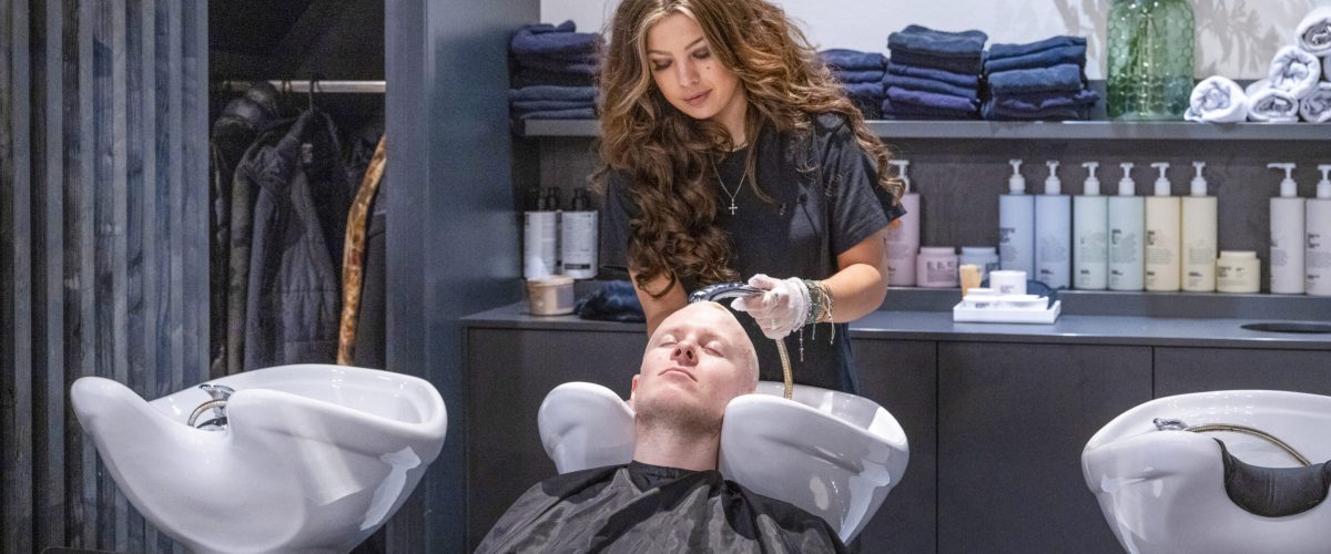 Hairstylist washing a client's hair at a salon.